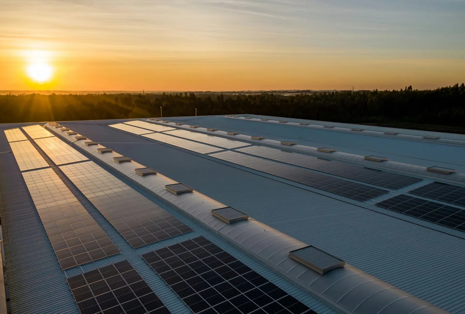 Installation photovoltaïque sur la toiture d'un bâtiment d'activité au coucher du soleil